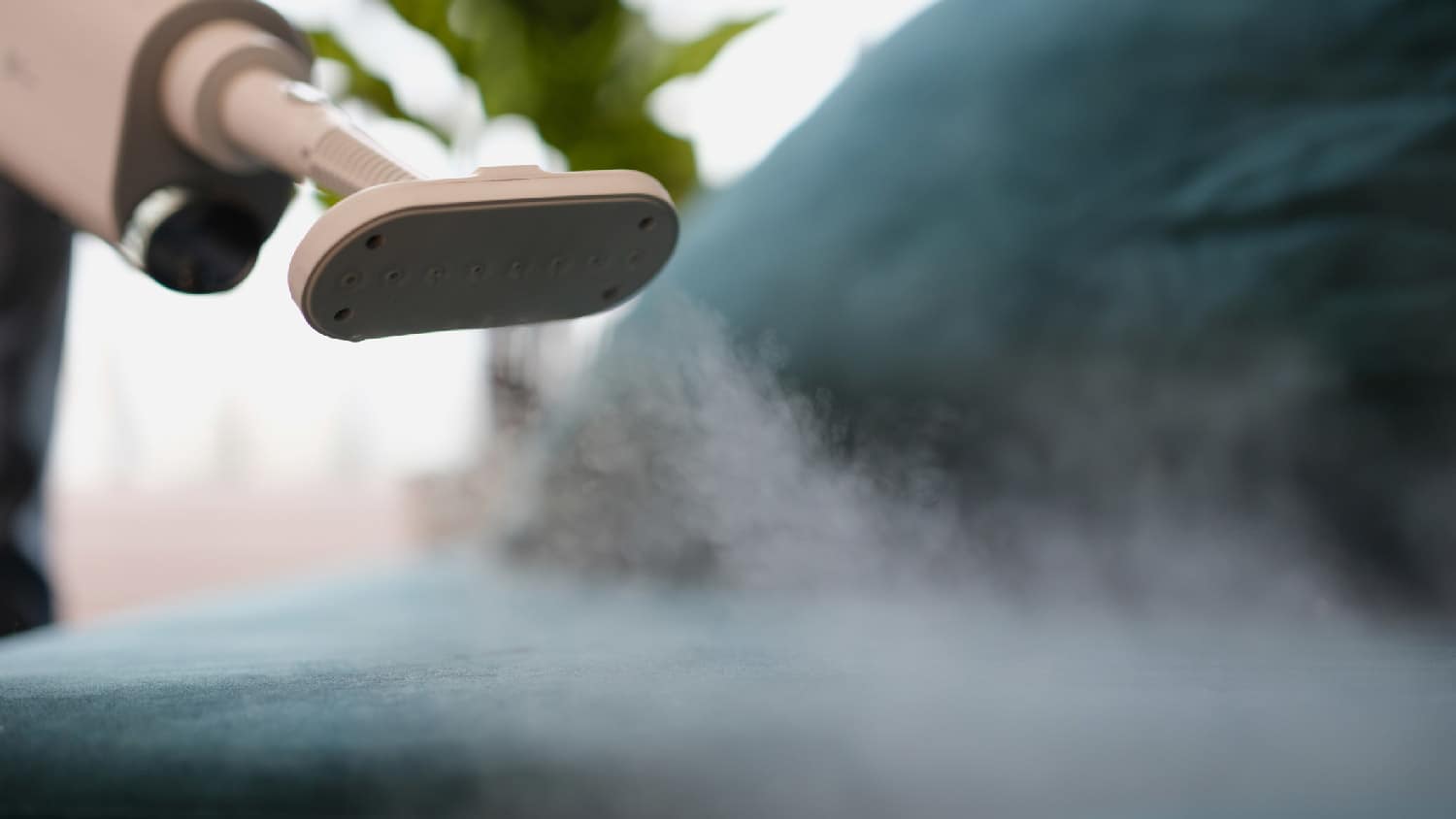 A person cleaning upholstery with steam