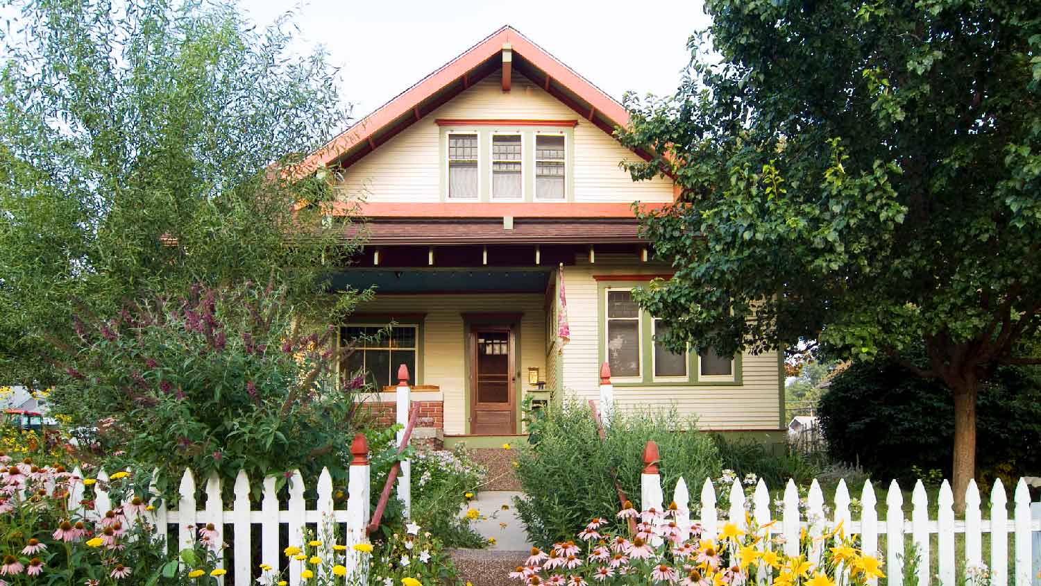 A bungalow with a lovely garden and a white picket fence