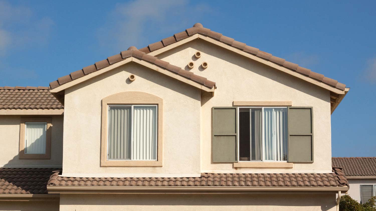 The exterior of a stucco house against the blue sky