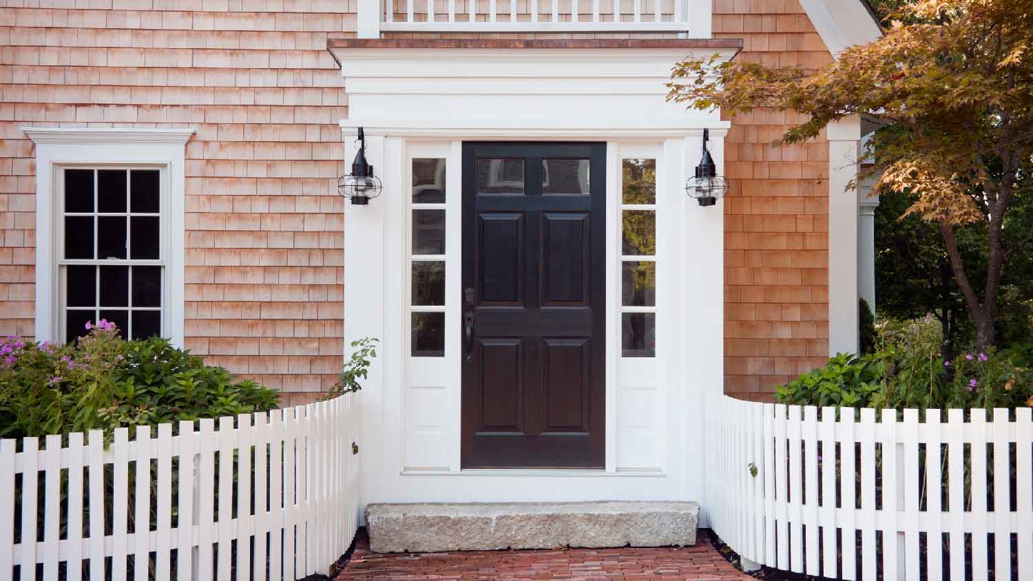 A house with a black exterior door and white picket fence
