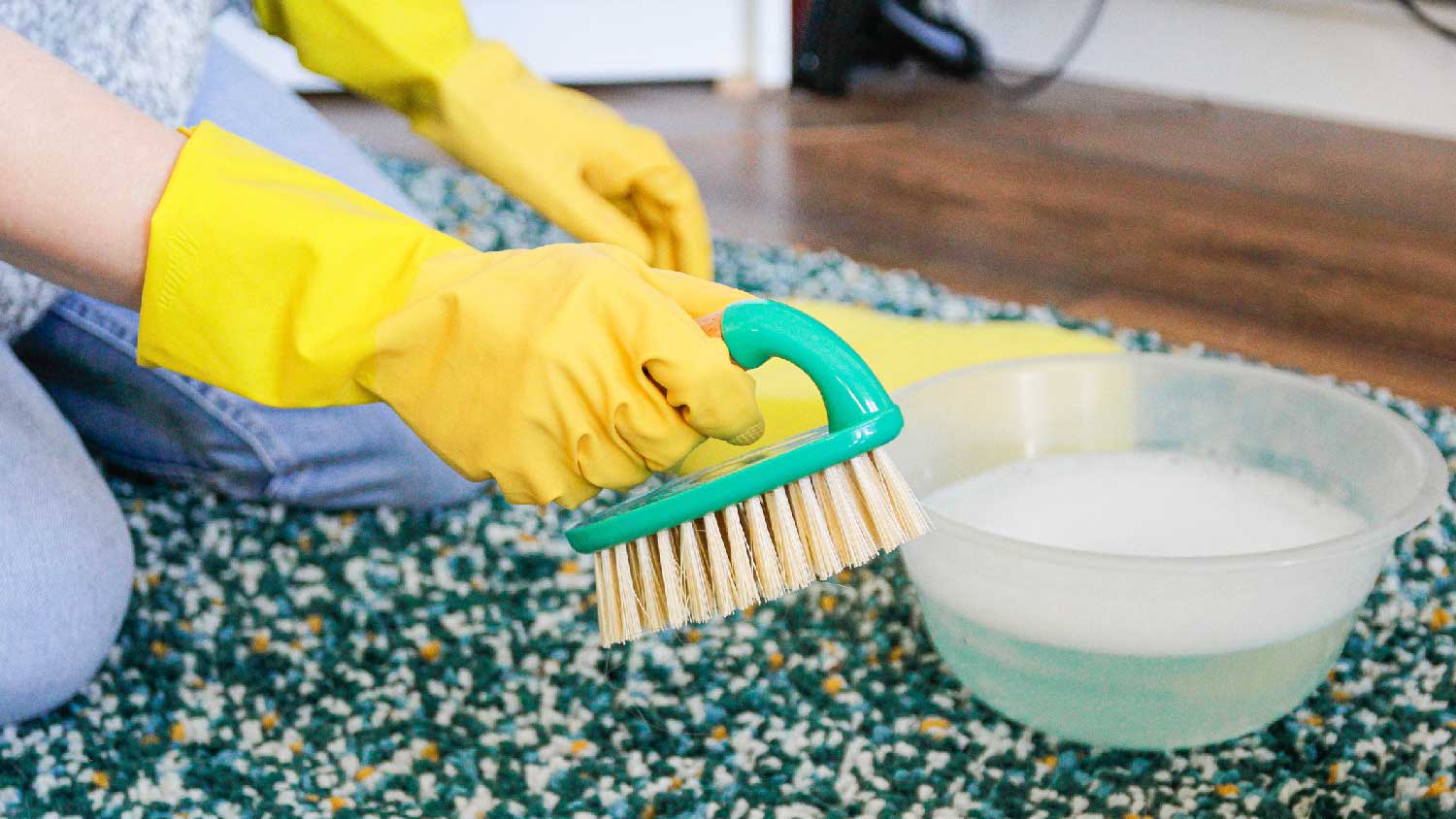 A woman cleaning a rug with a brush and water