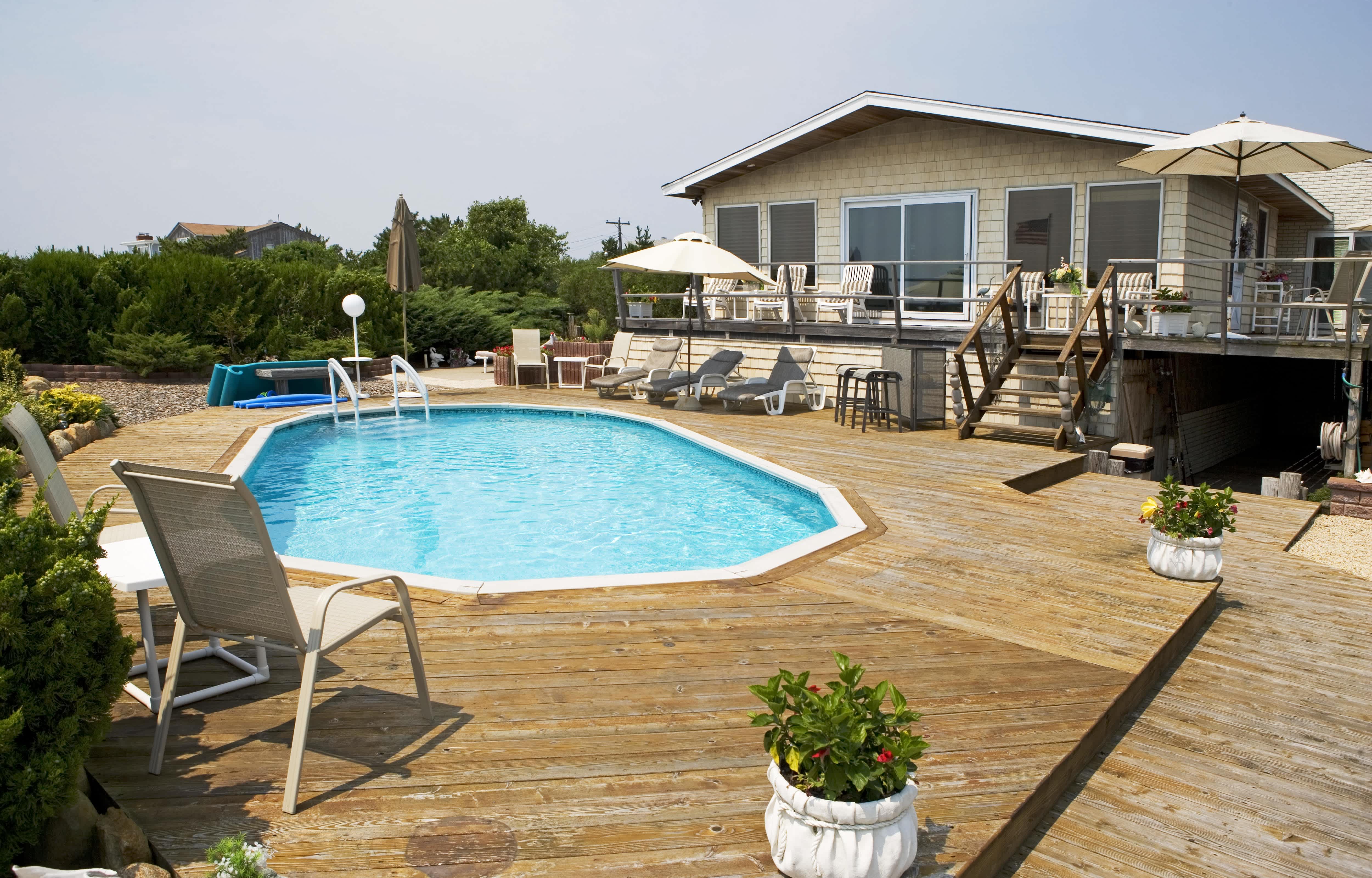 An above-ground pool surrounded completely by a wooden deck
