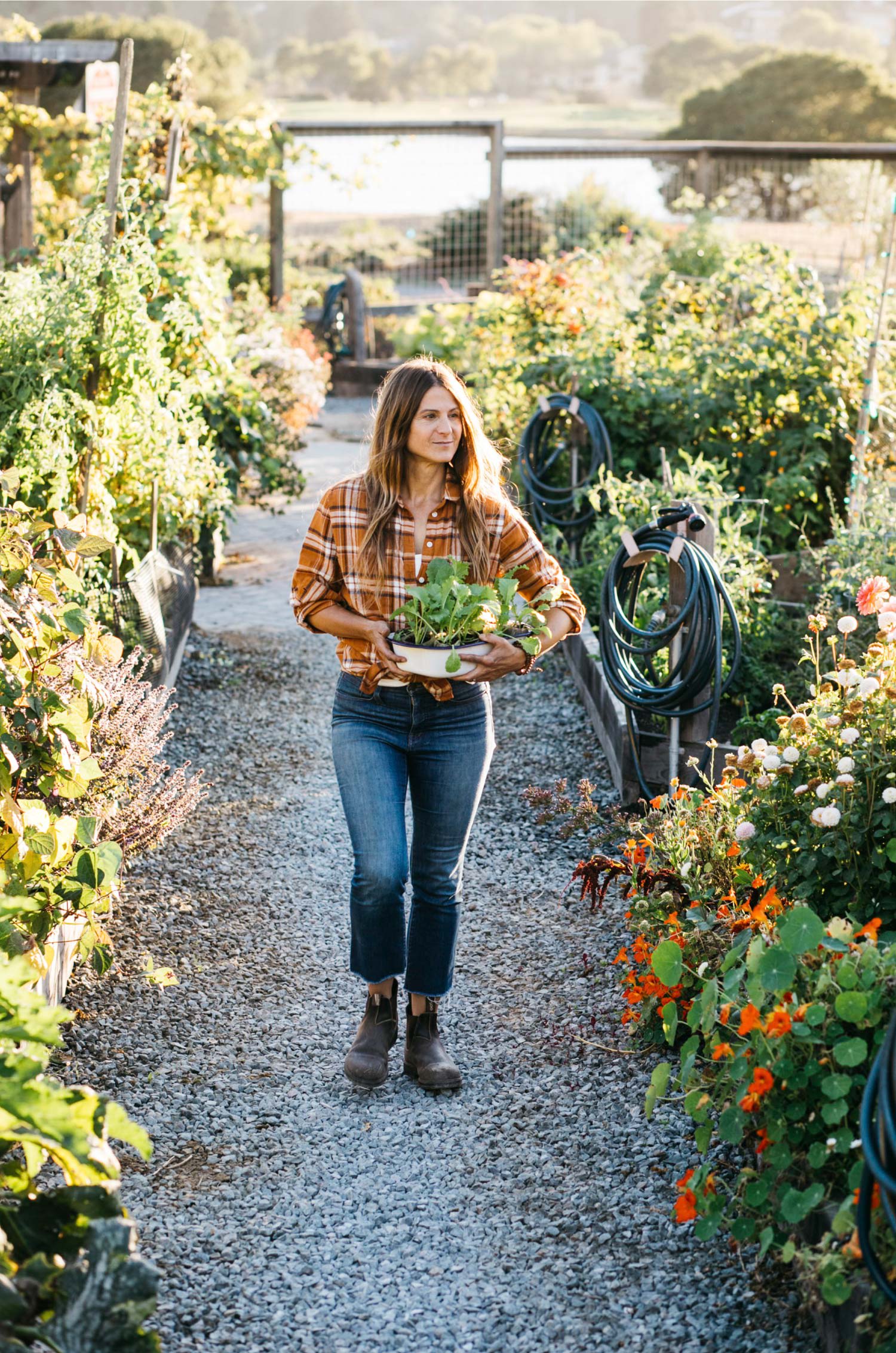 Woman holding plant while walking through garden
