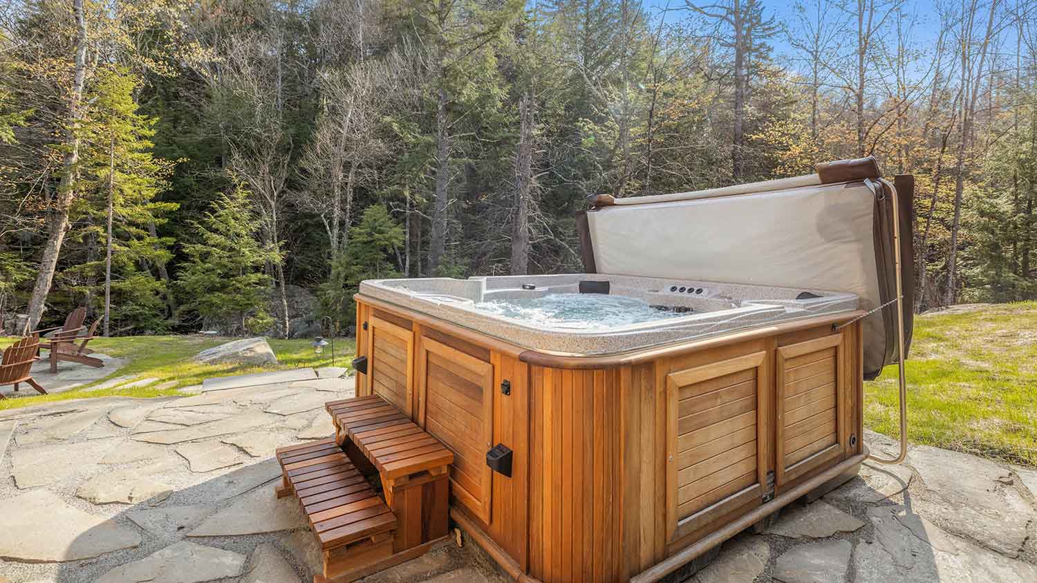 Wooden hot tub in a yard surrounded by trees