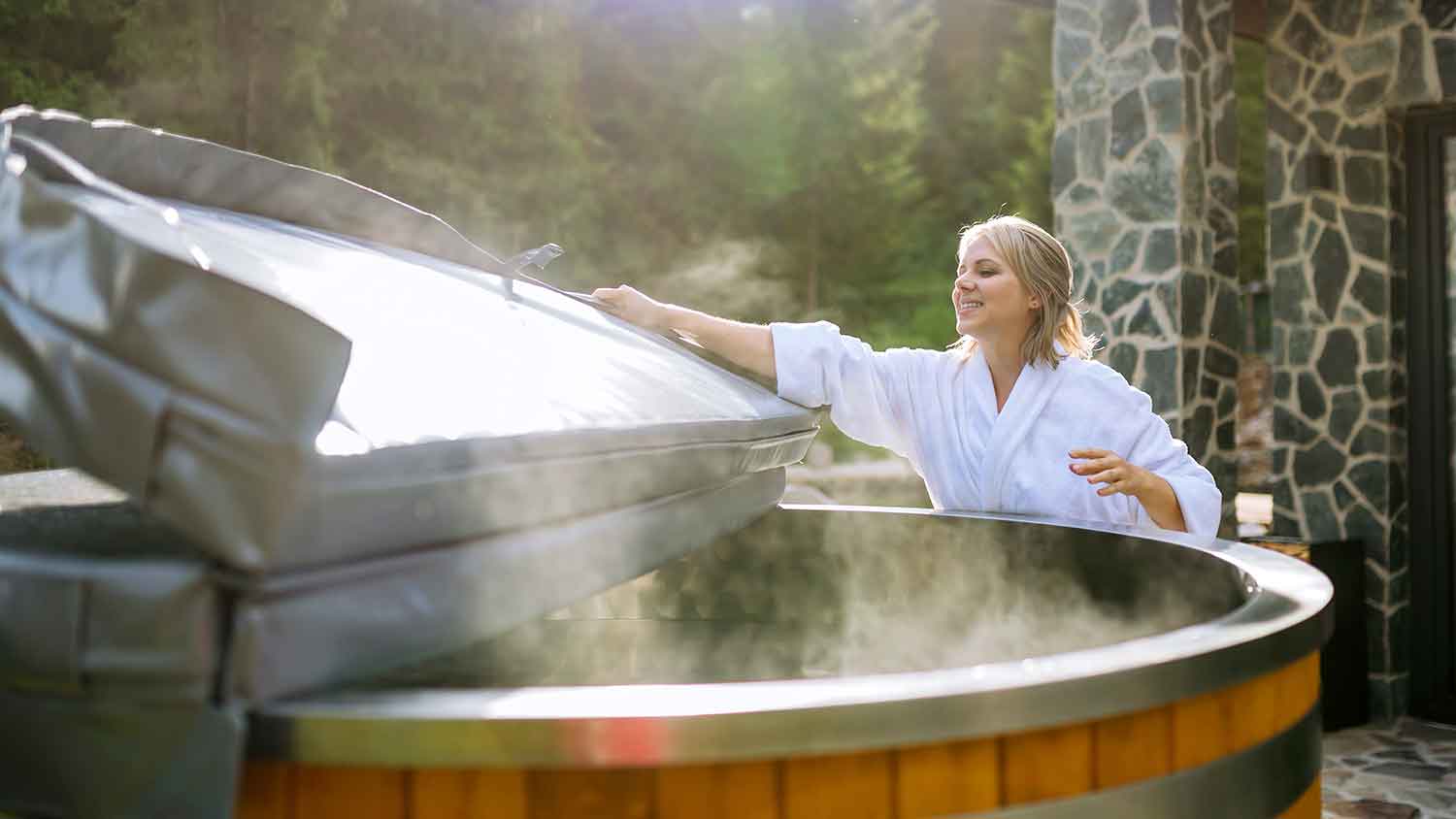 Woman in bathrobe removing hot tub cover