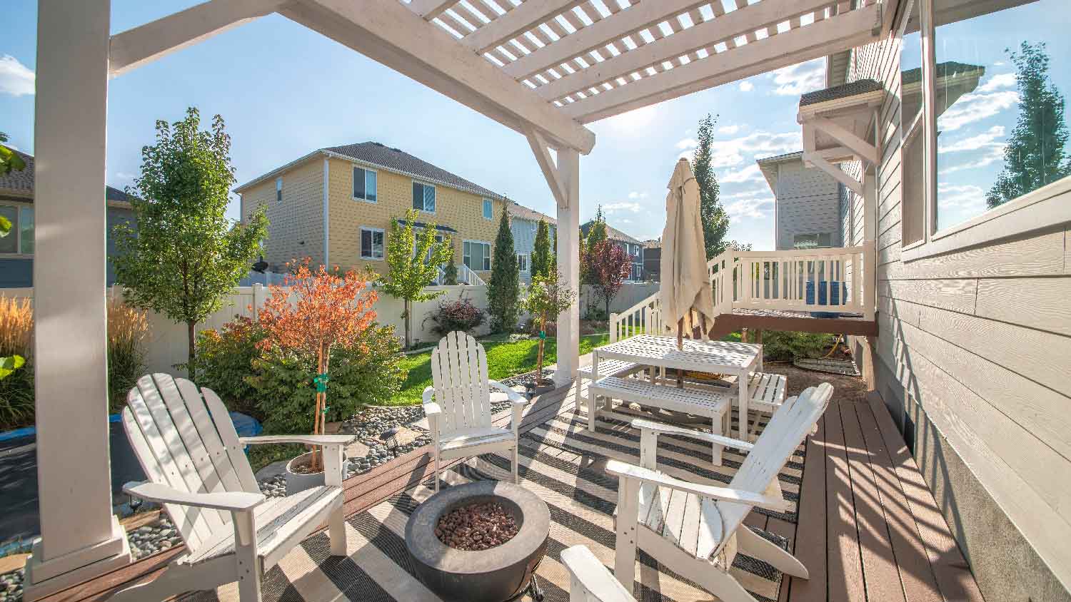 A fire pit on a patio under a wooden pergola