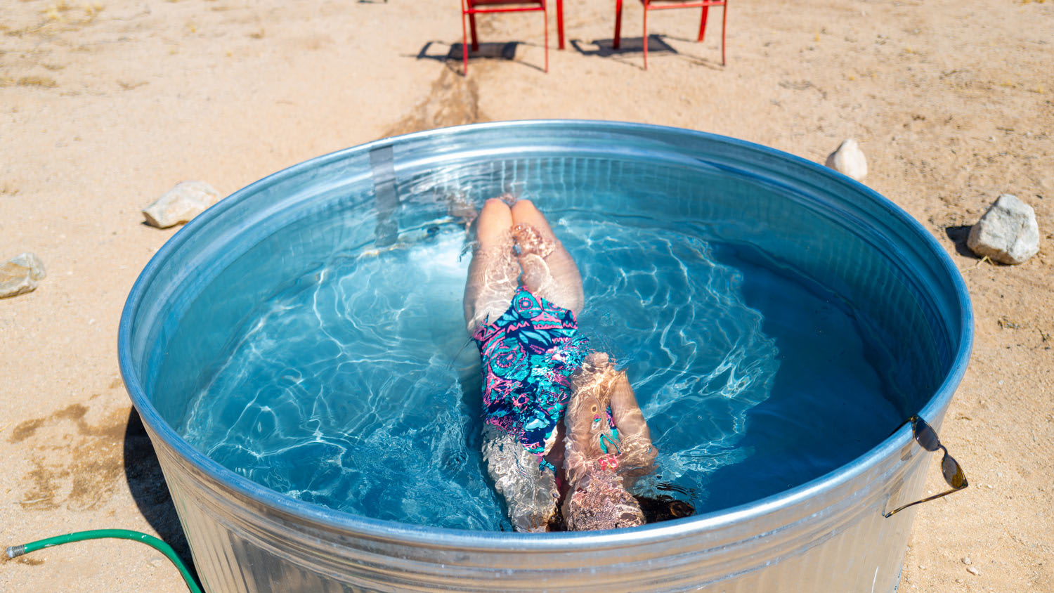 A girl submerges underwater in a small outdoor tub pool