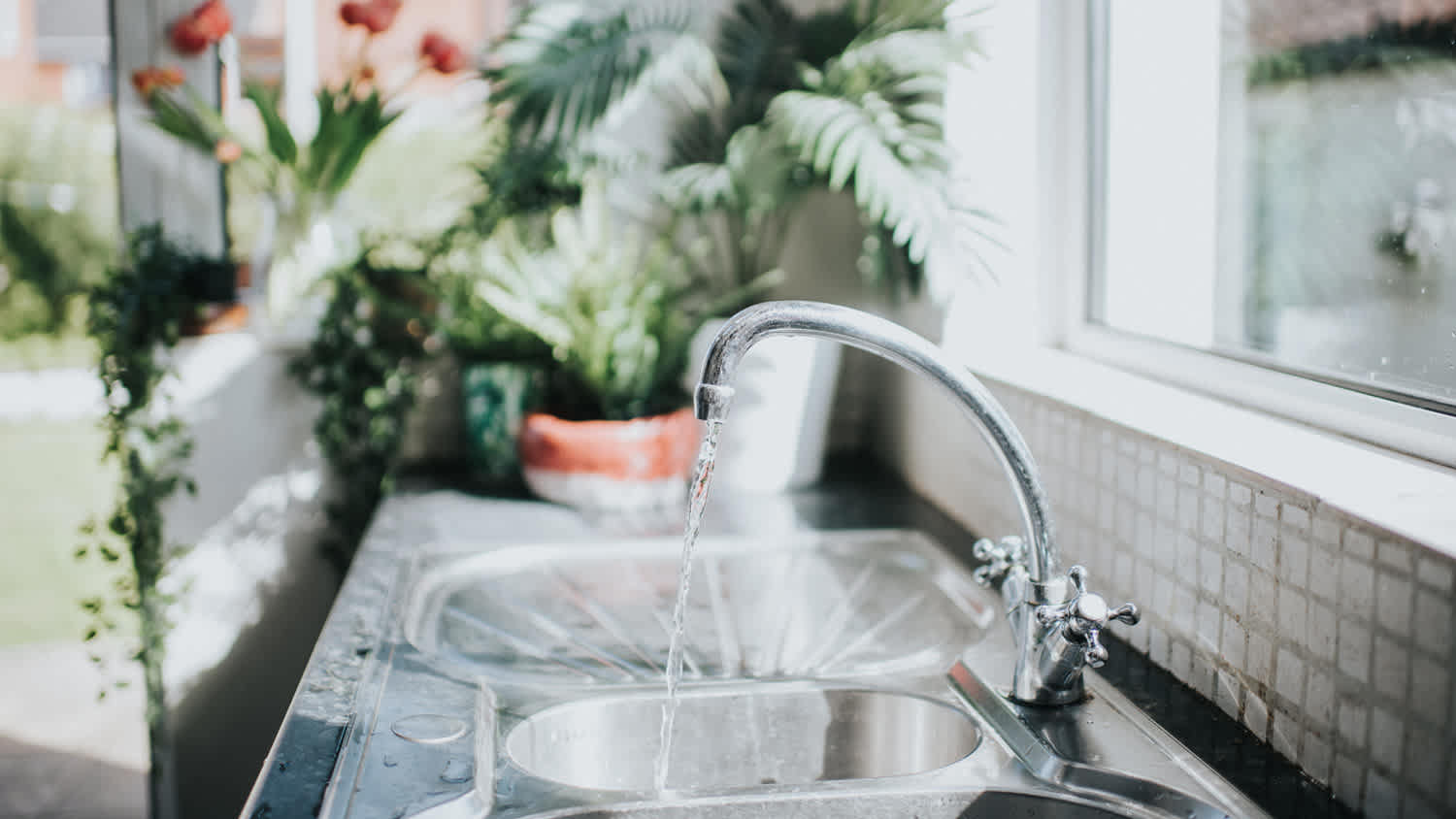 A silver tap running water on a sunny day