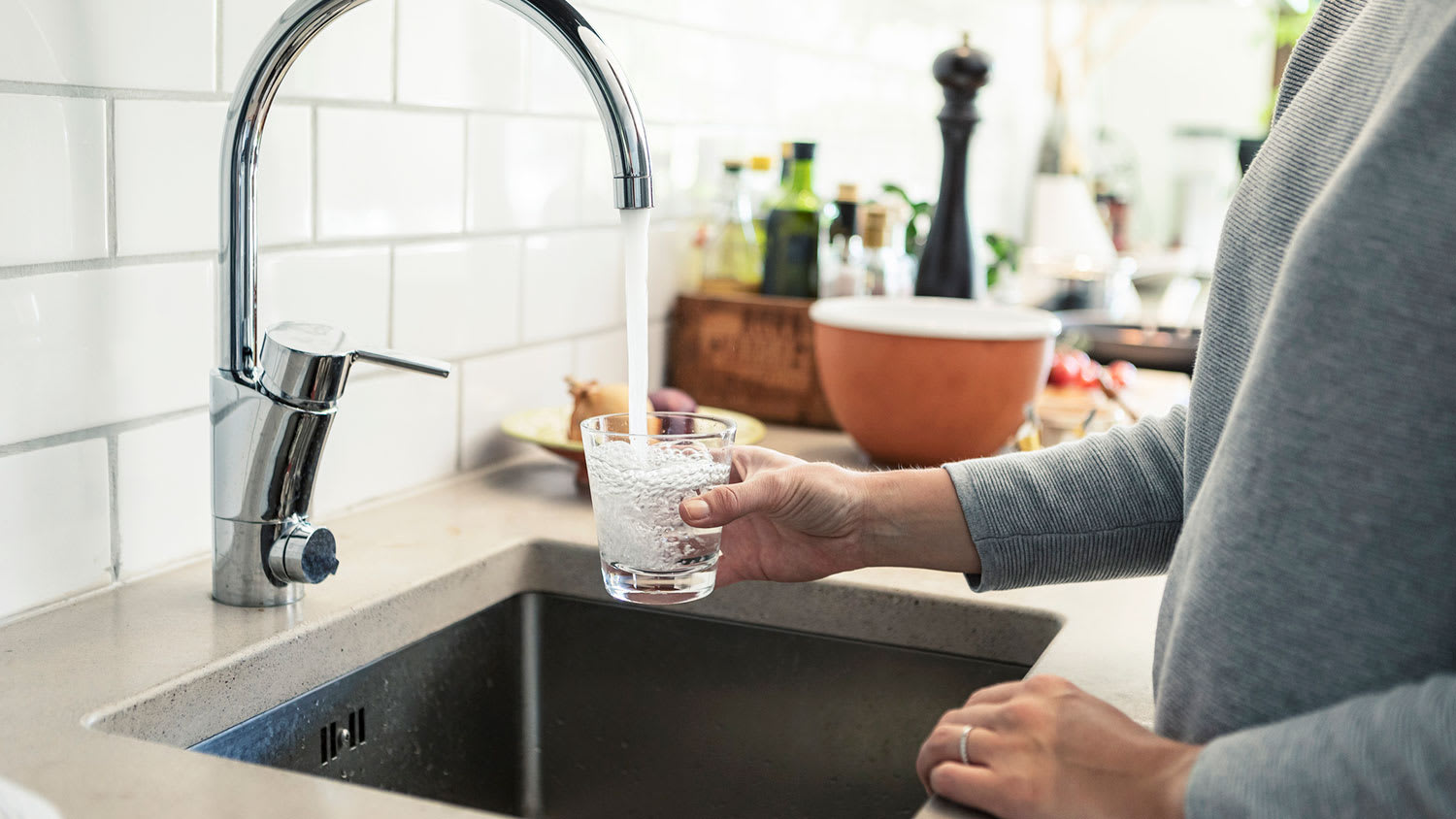 Woman in the kitchen filling up glass with tap water