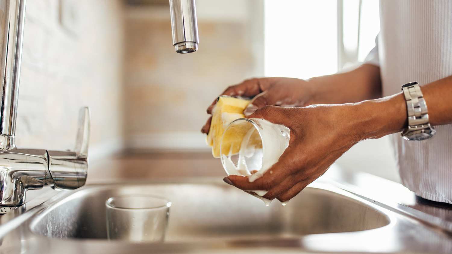 Close-up of a woman’s hands washing glassware