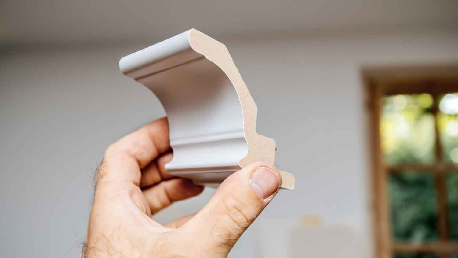 Hand holding a piece of MDF crown molding