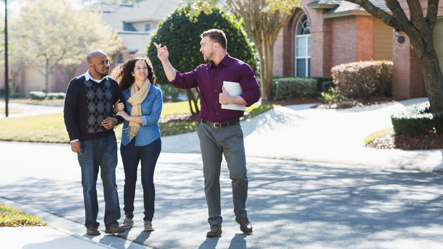 A couple walking with a contractor on a residential road