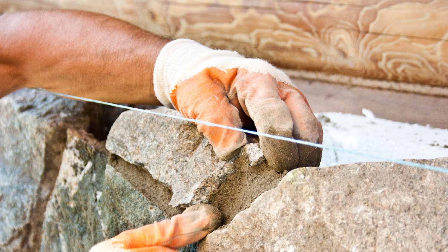 Close-up of a person building a stone wall