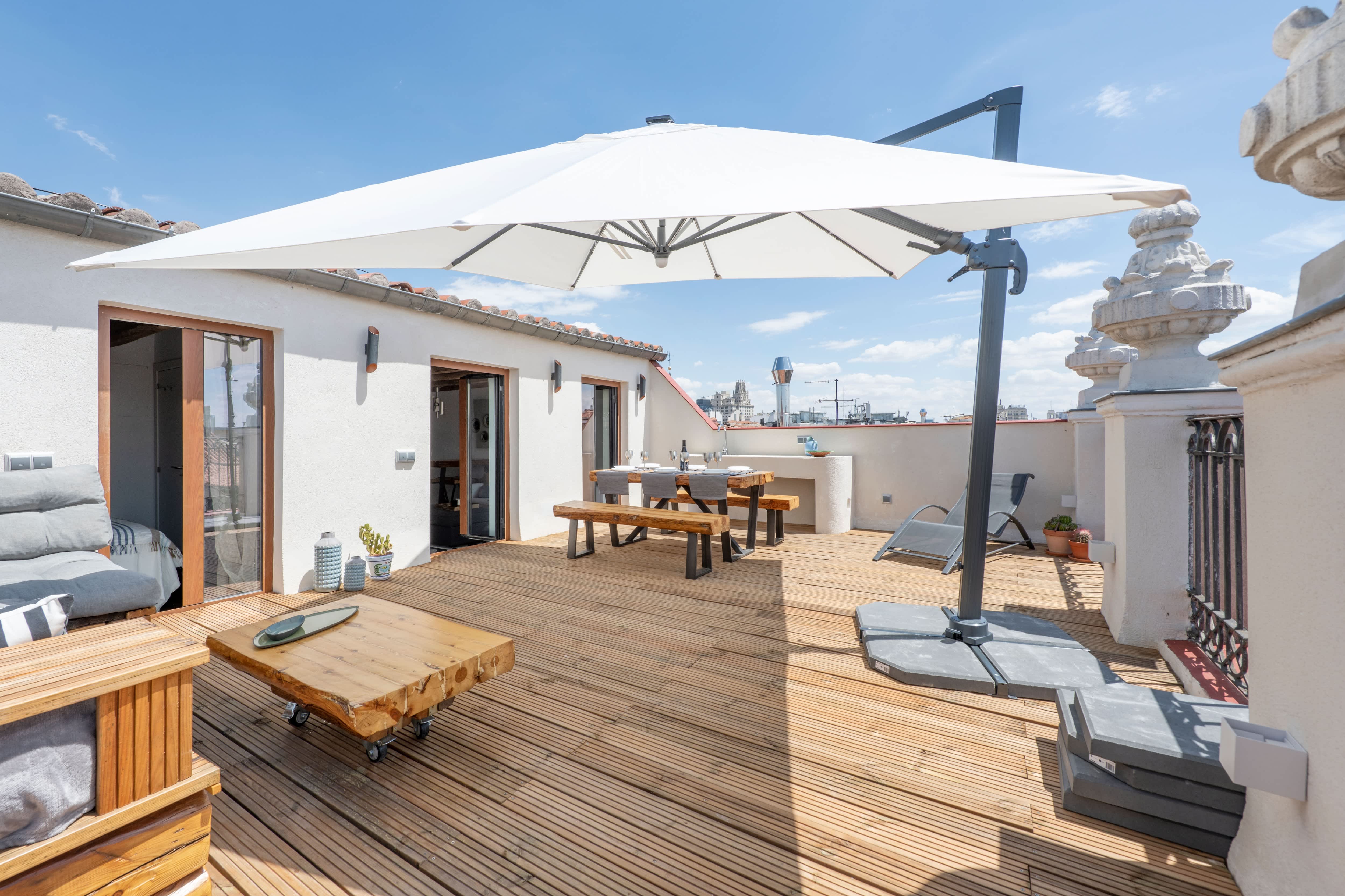 A large terrace umbrella on a wooden deck with a dining table