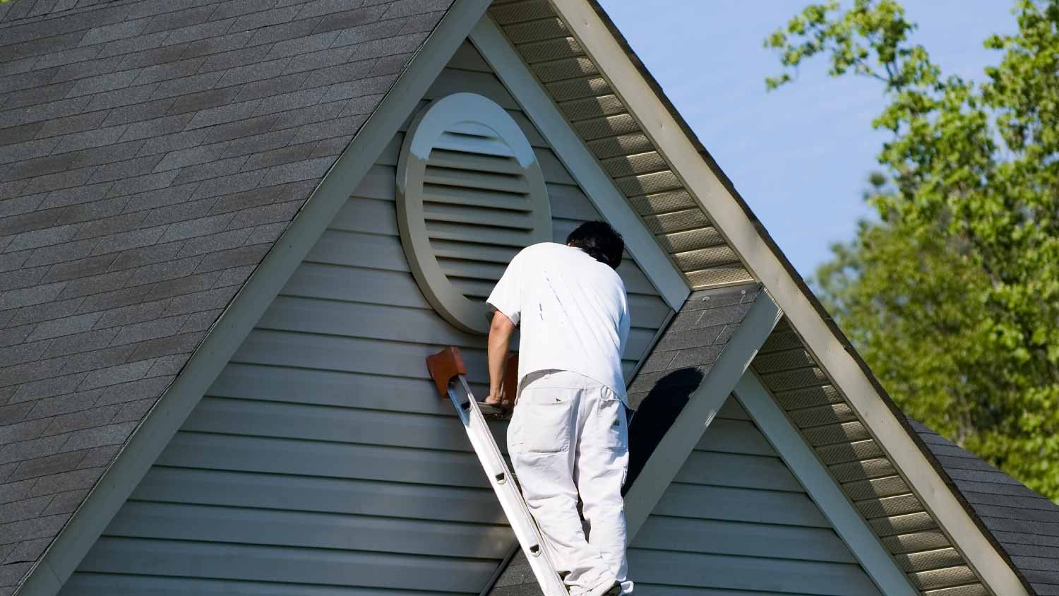 Painter working at the top of a house