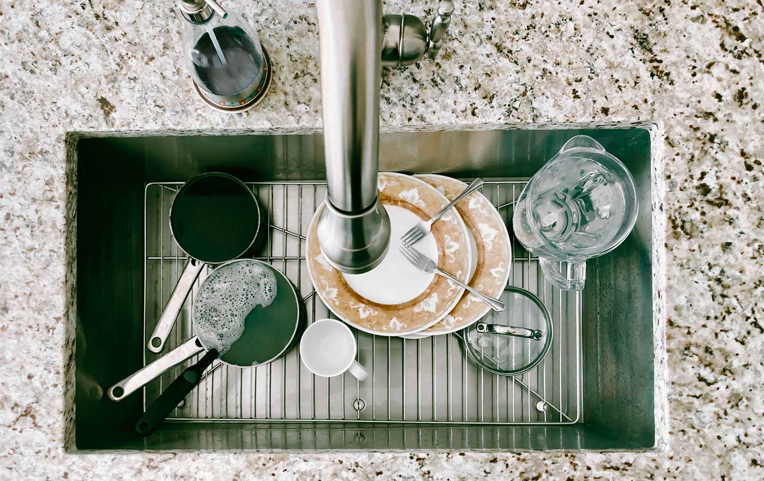 Dirty dishes sitting in a sink on a metal grid