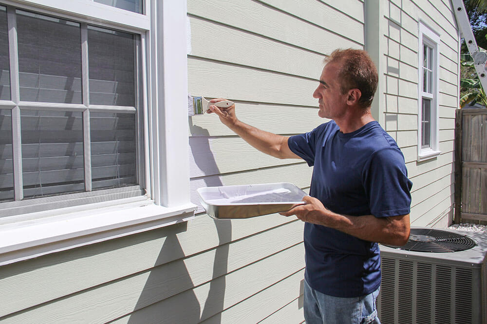 Man painting house siding