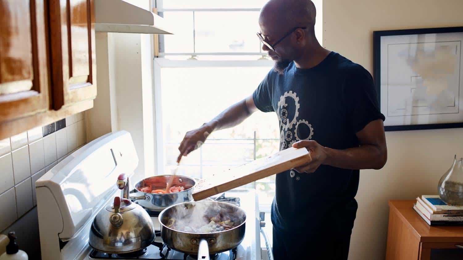 : Man holding cutting board cooking on stove