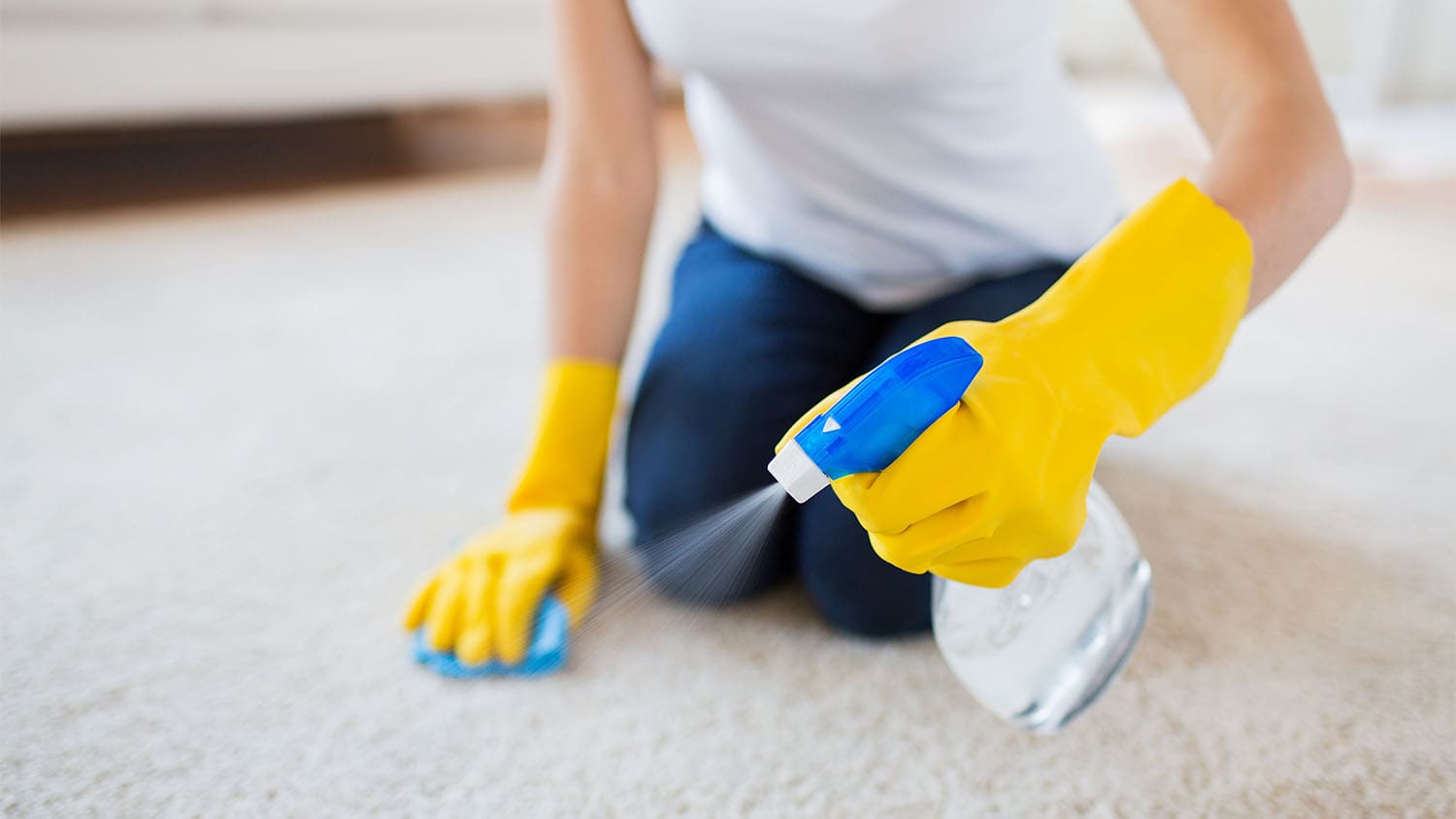 woman spraying carpet to prevent stains
