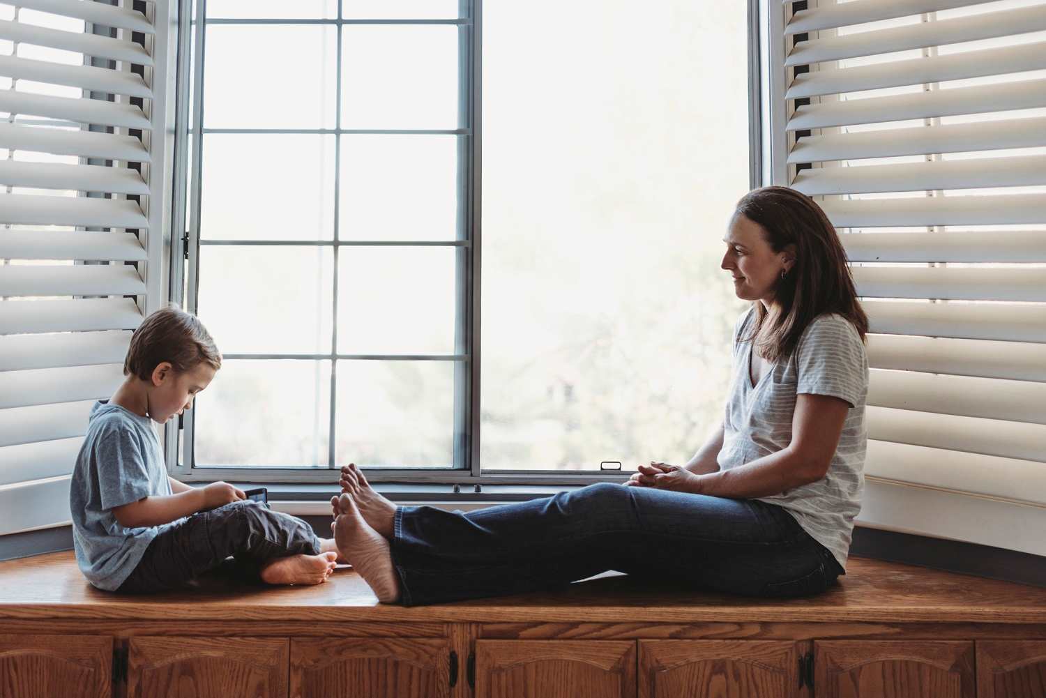 boy and mother sitting in front of a window