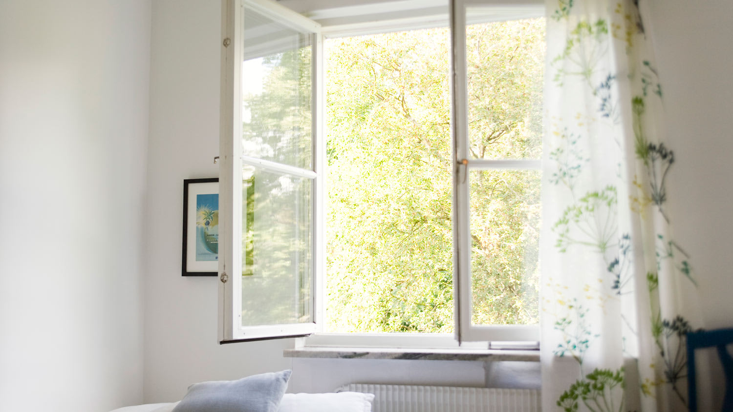An open small window with curtain in a bedroom