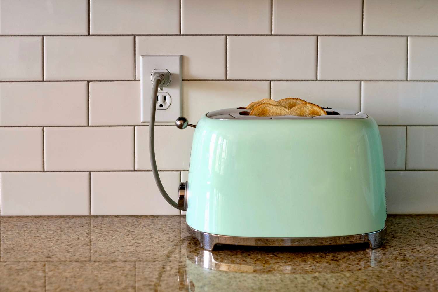 Mint green toaster plugged into outlet on kitchen countertop