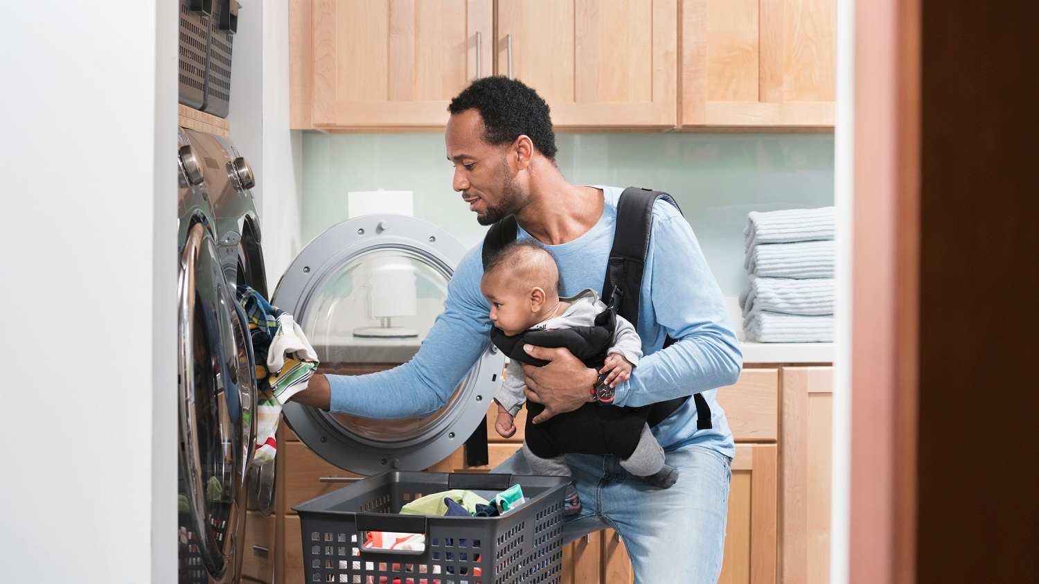 Father with son in baby carrier doing laundry