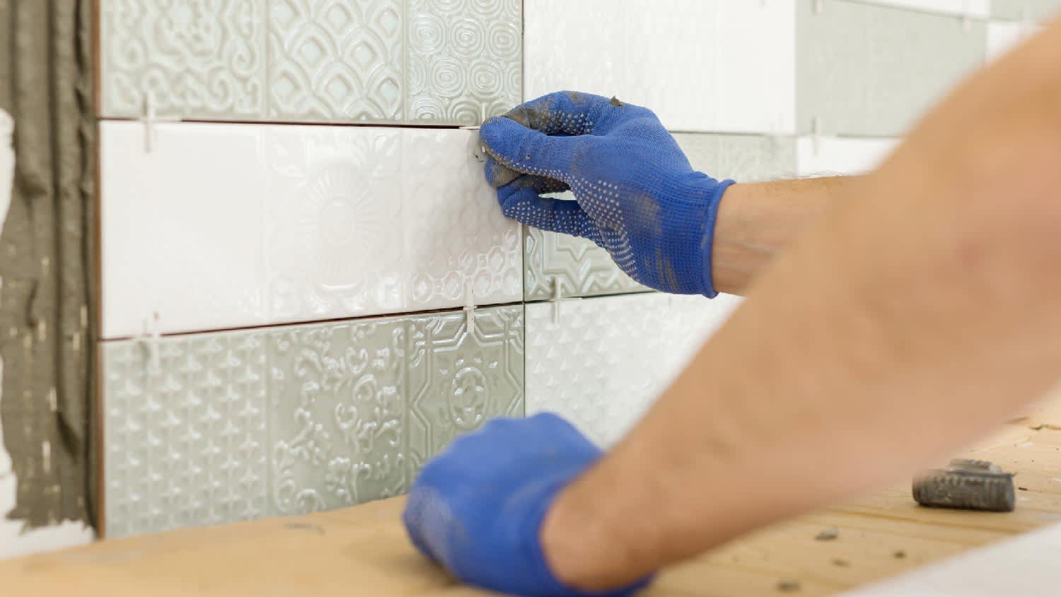A person placing tile spacers between ceramic tiles