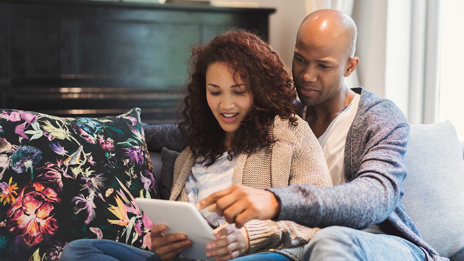couple cuddling on sofa using tablet