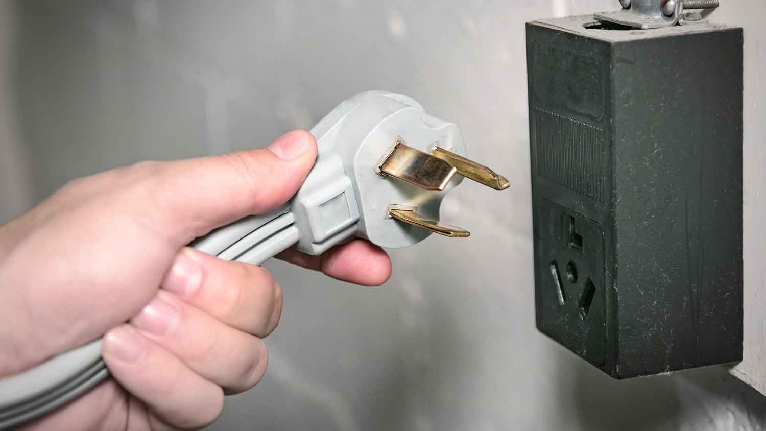 Hand holding a 240v power cord