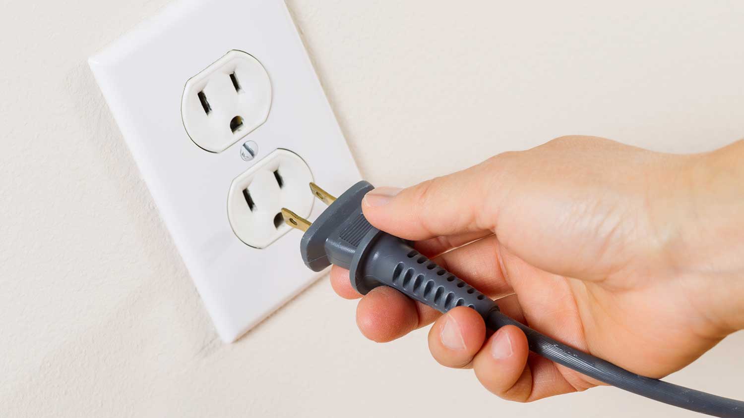 Hand plugging in power cord into electrical outlet