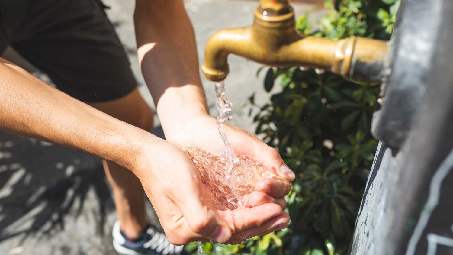A man washing his hands in an outdoor spigot