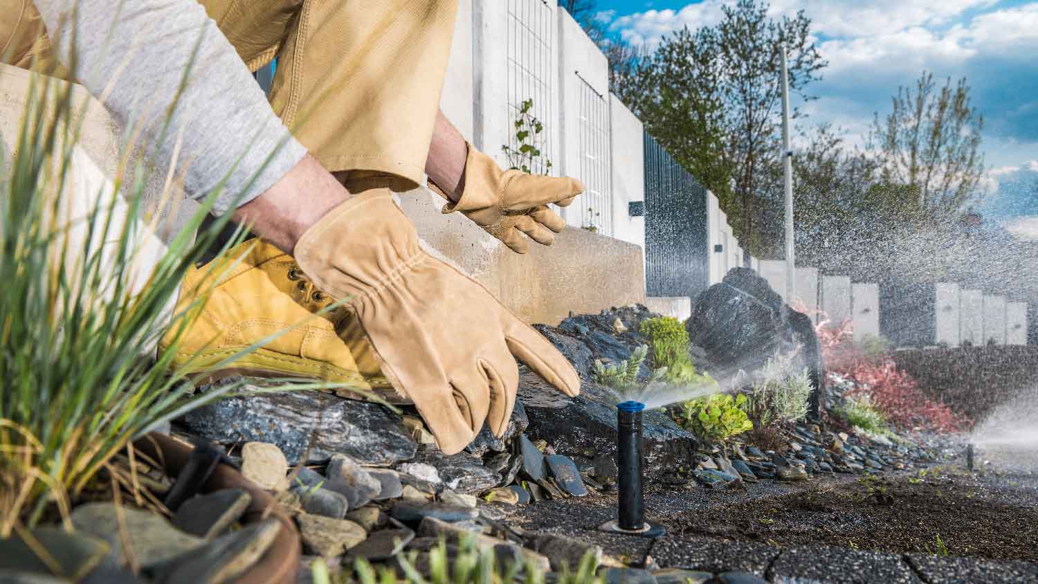 A person adjusting a sprinkler head