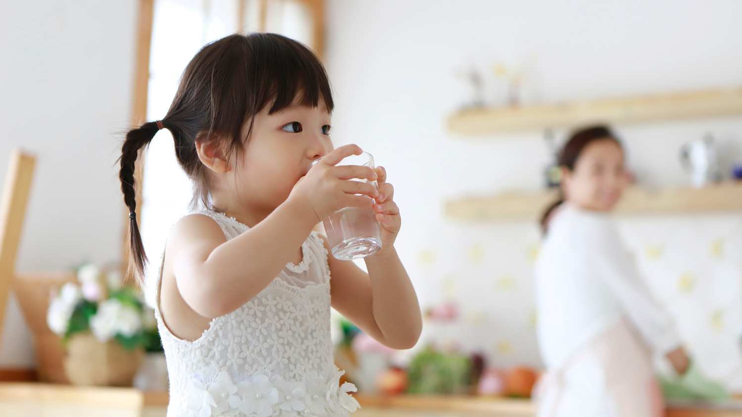 A little girl drinking water from a glass
