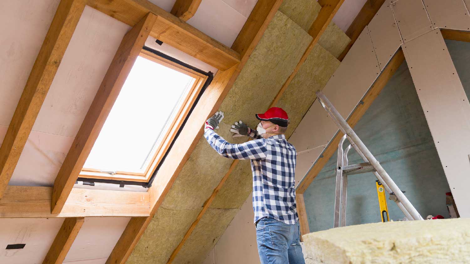 A professional installing rock wool insulation in the attic