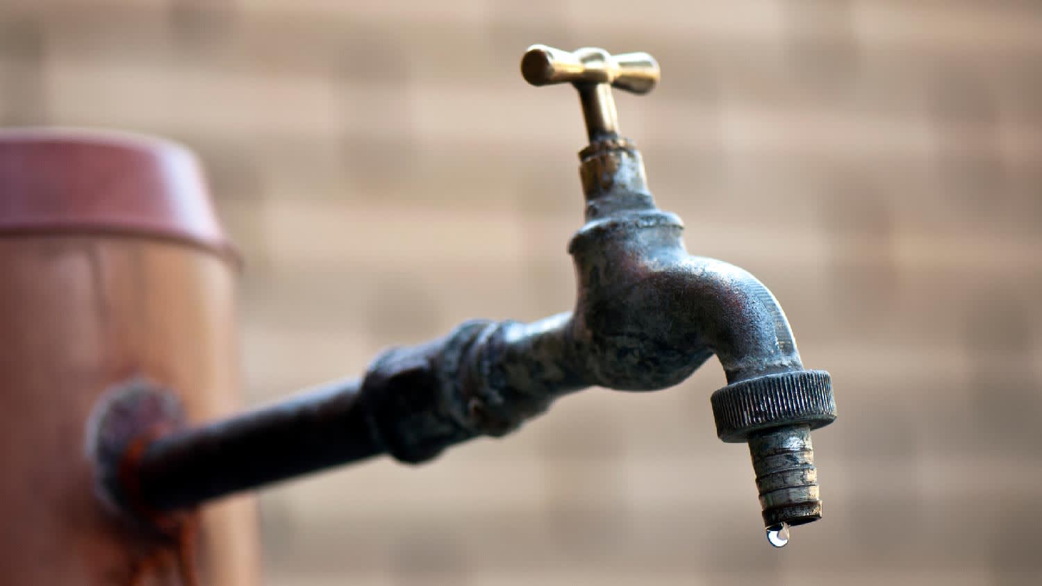 An outdoor spigot with one drop of water
