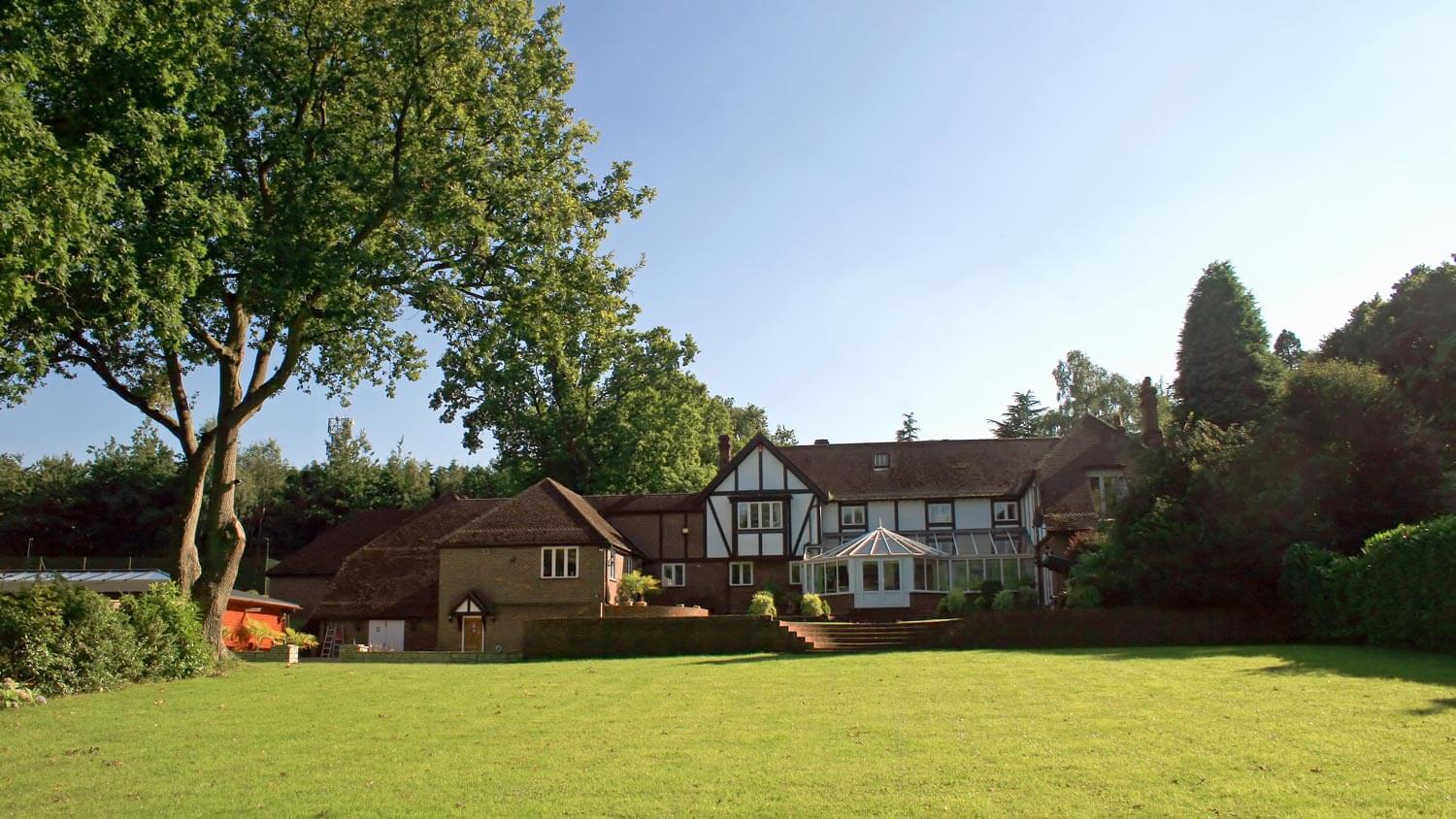A tudor house with a large tree in the garden