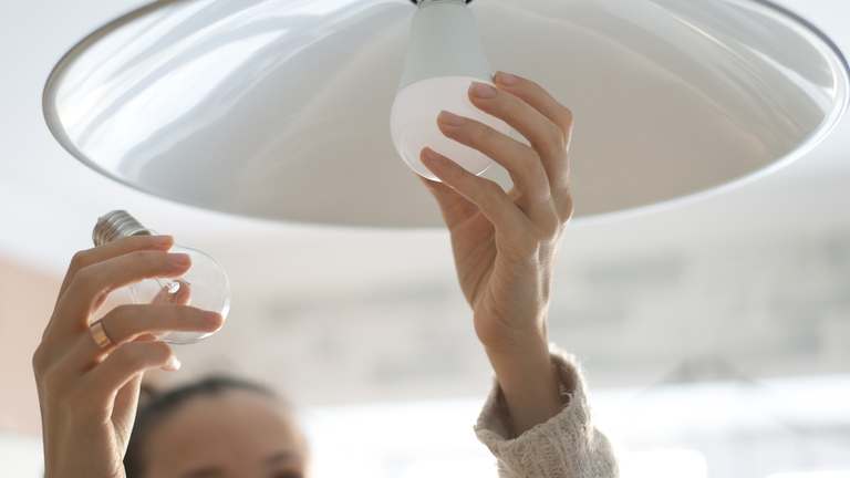 Woman replacing light bulb in lamp