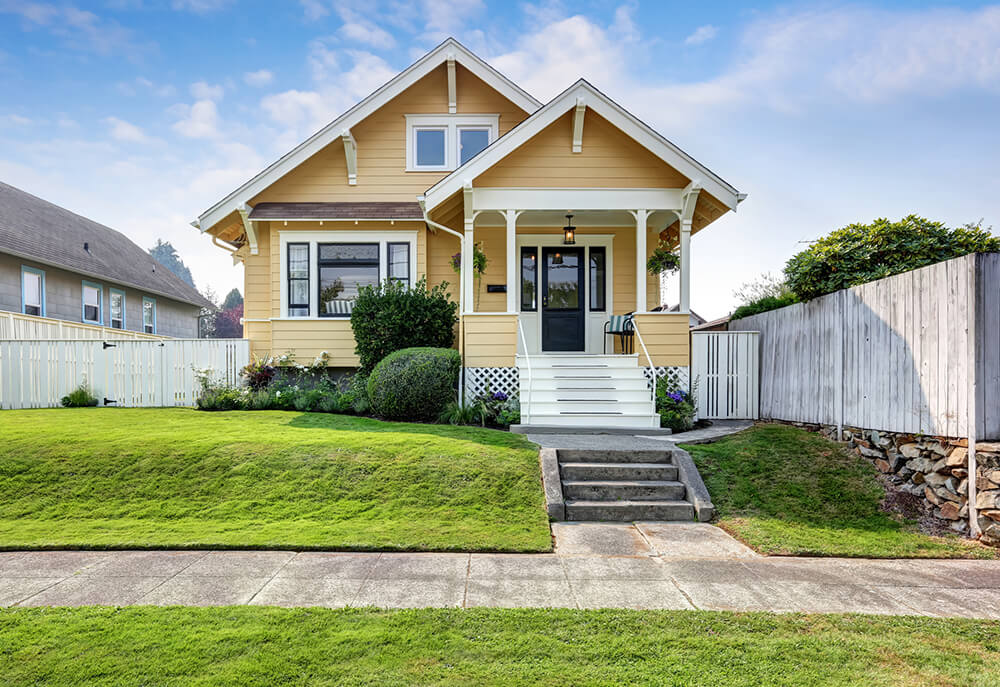 Craftsman-style house with yellow exterior paint and white accents