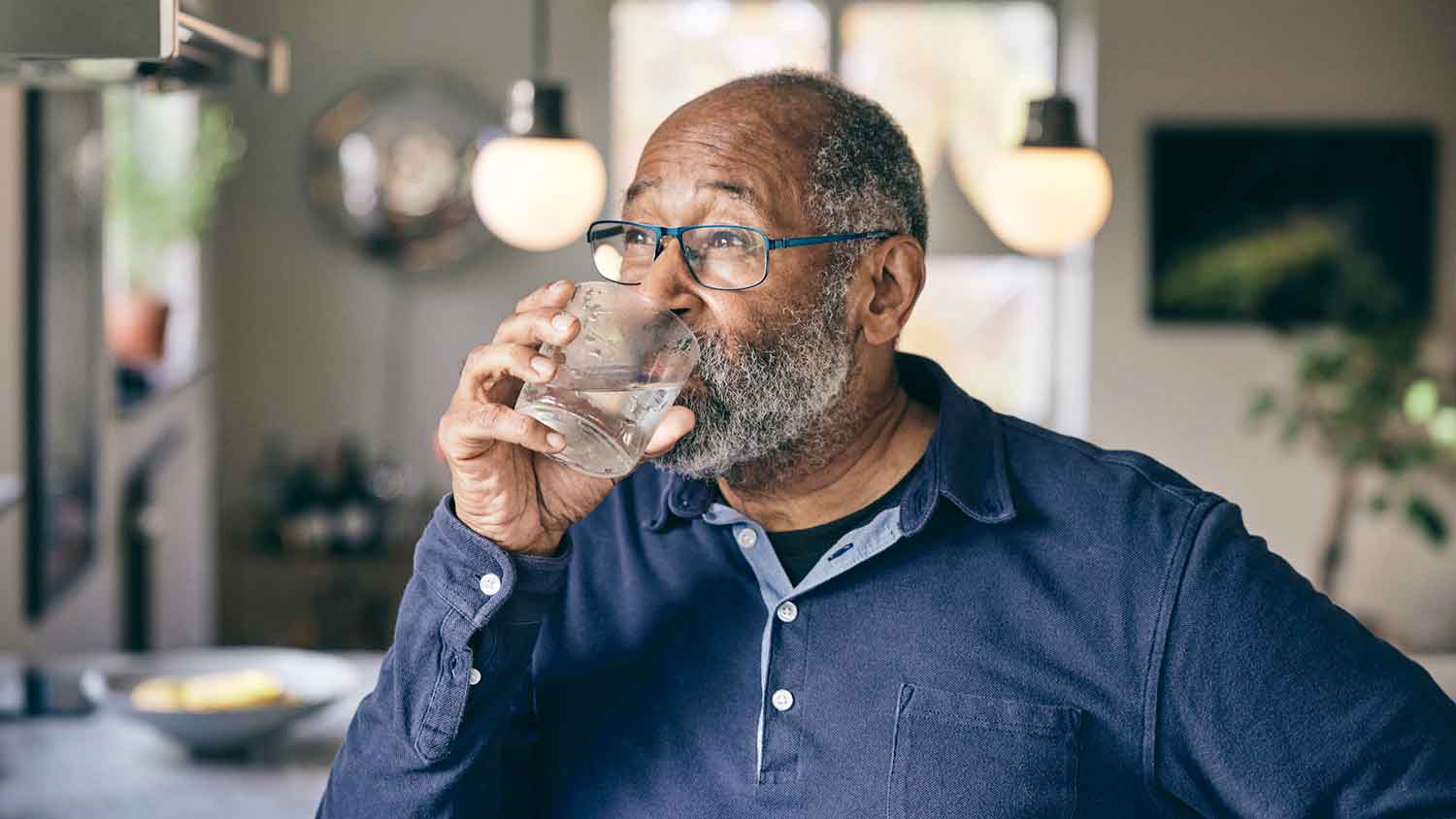 Senior man drinking filtered water at home