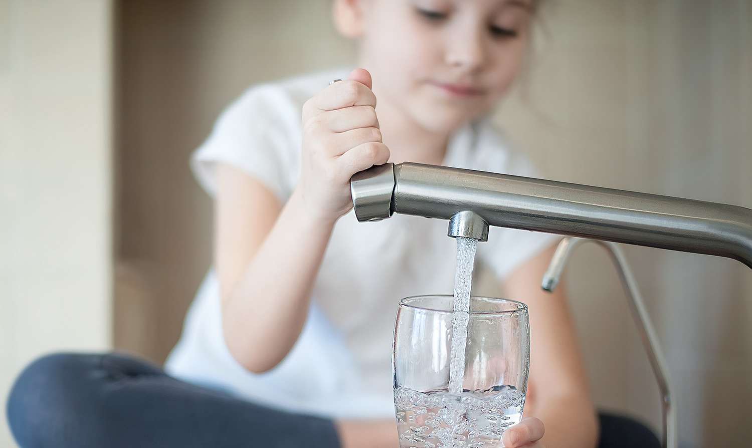 Little girl pours water into glass