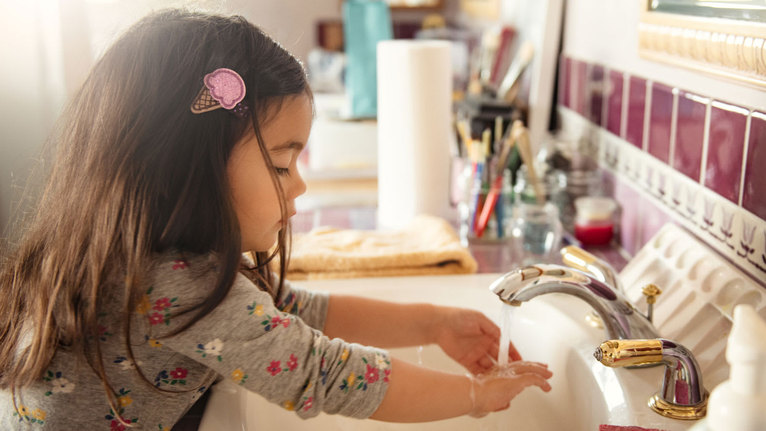 A toddler girl washing her hands in the sink