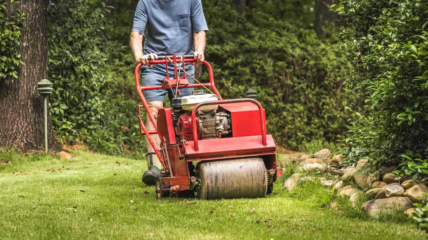 man using an aerator machine on grass
