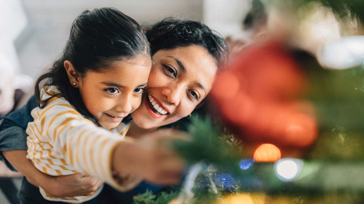 A mother and her daughter decorating the Christmas tree
