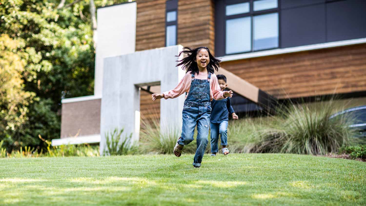 A sister and her brother running on the lawn