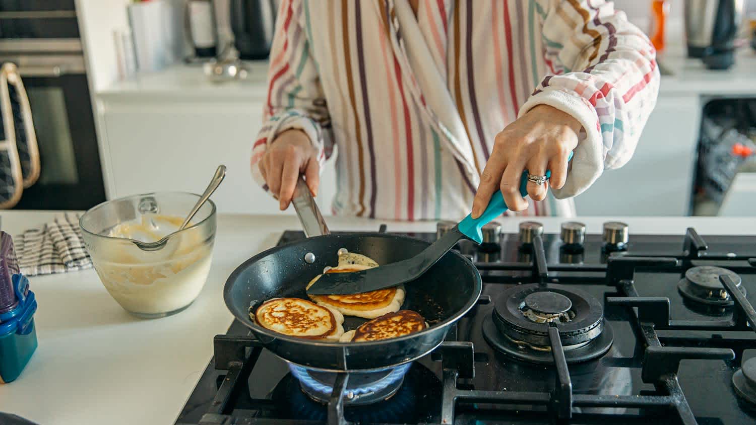 A woman cooking pancakes on a gas stove