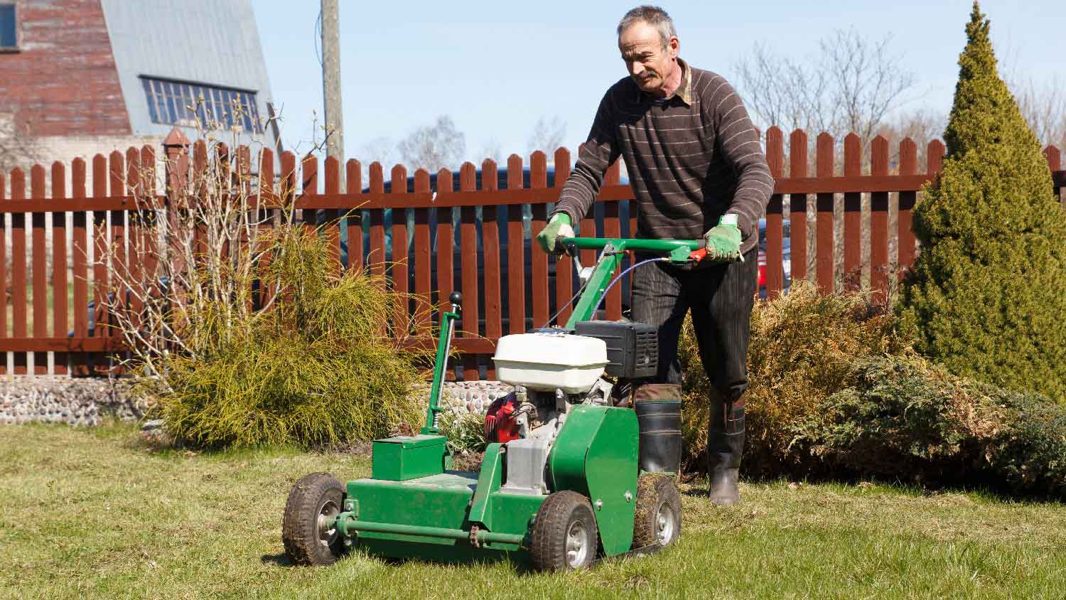 A man using a gas powered core aerator