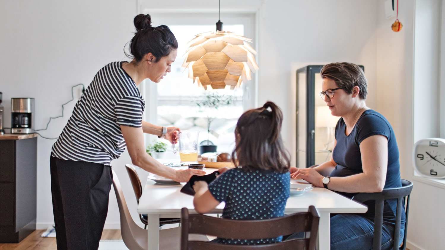 Female serving food to girl and woman at dining table