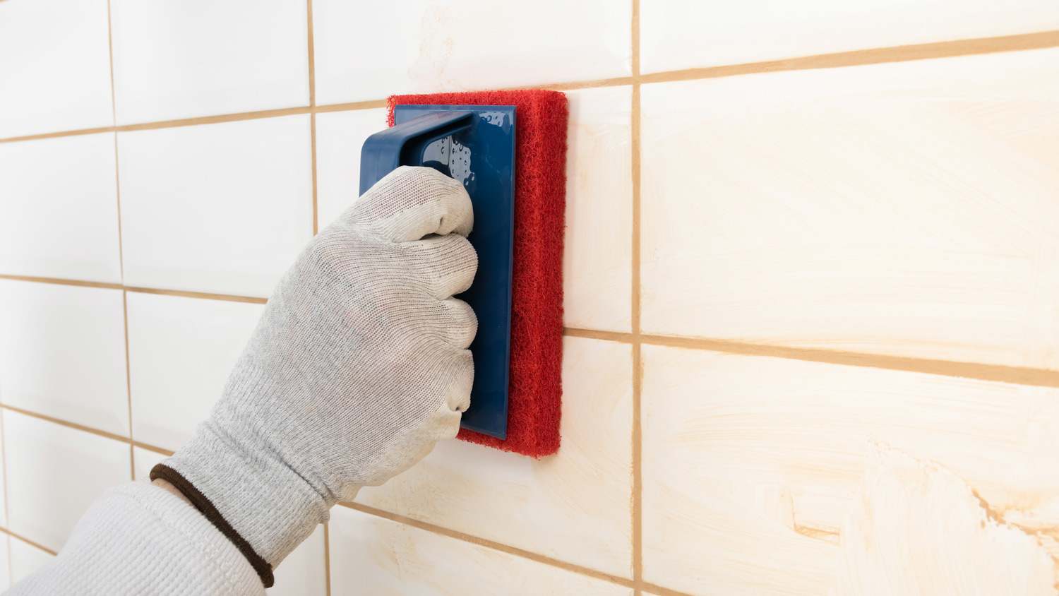 Close-up of a hand cleaning the shower grout