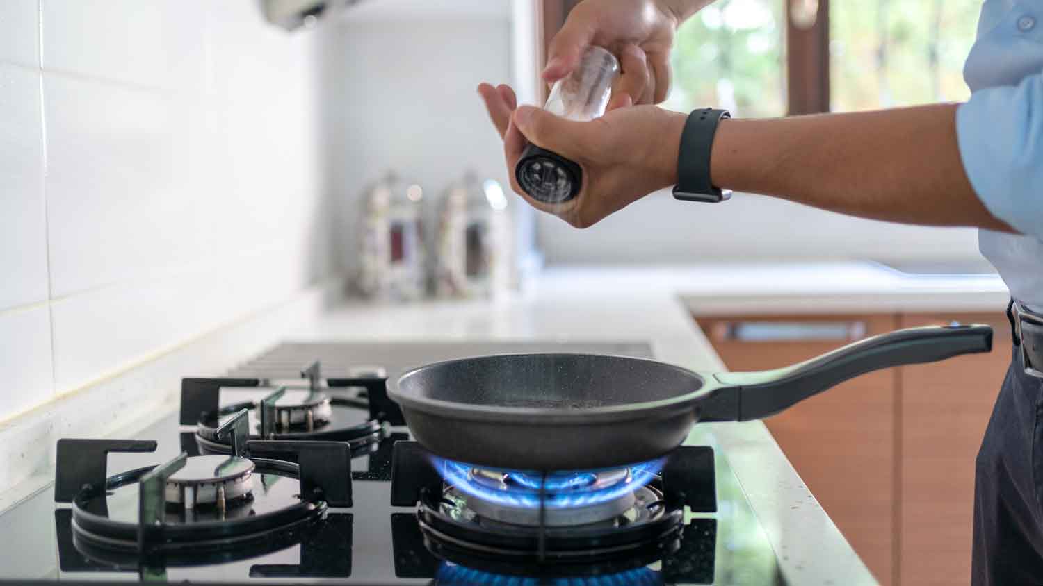 Man adding salt in a frying pan